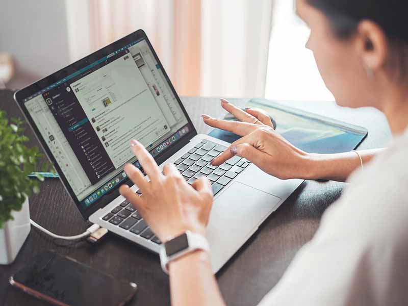 Eine Frau tippt auf ihrem Laptop eine Nachricht in einen Chat.