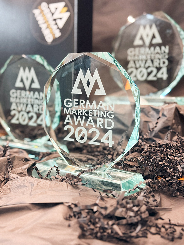 Drei Exemplare des German Marketing Awards 2024.