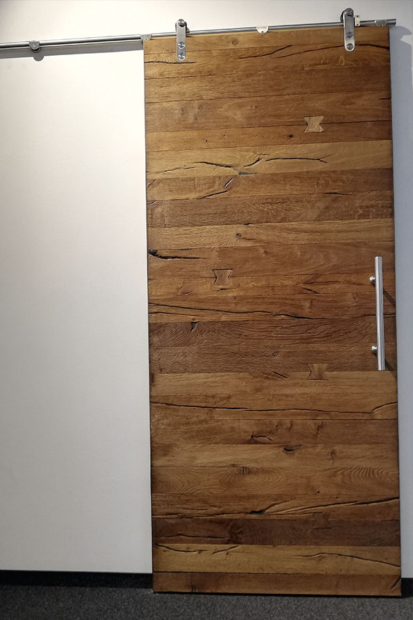 Eine massive Holztür mit modernem Stahlgriff.