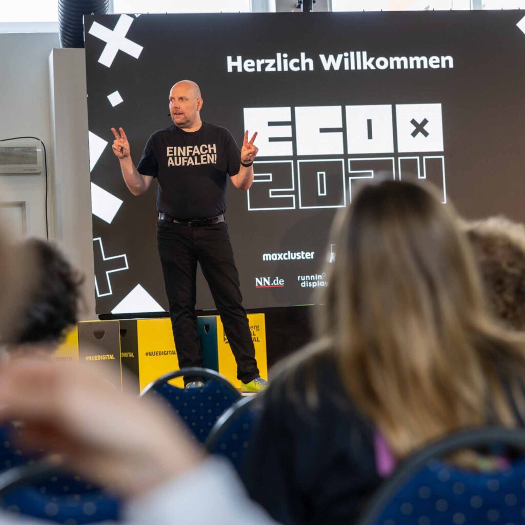 Ein Mann auf einer Bühne, der zum Publikum spricht.