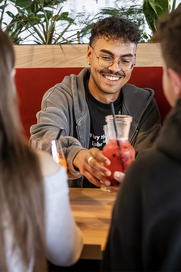 Ein junger Mann stößt fröhlich mit seinen Freunden an.