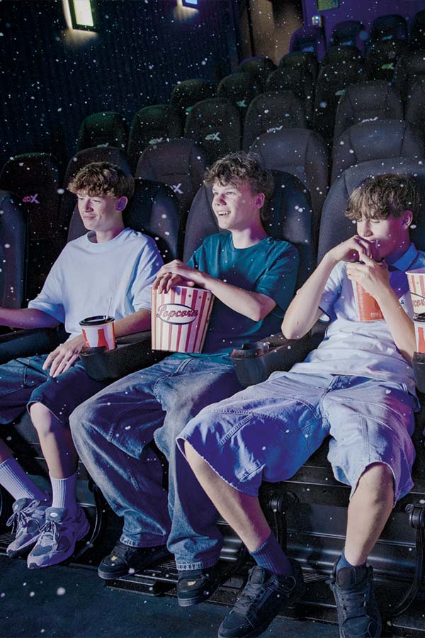 Drei Jugendliche sitzen fröhlich im Kino.
