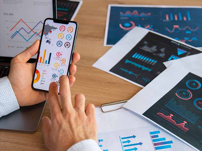 Eine Person schaut sich Analysen und Grafiken auf einem Smartphone an.